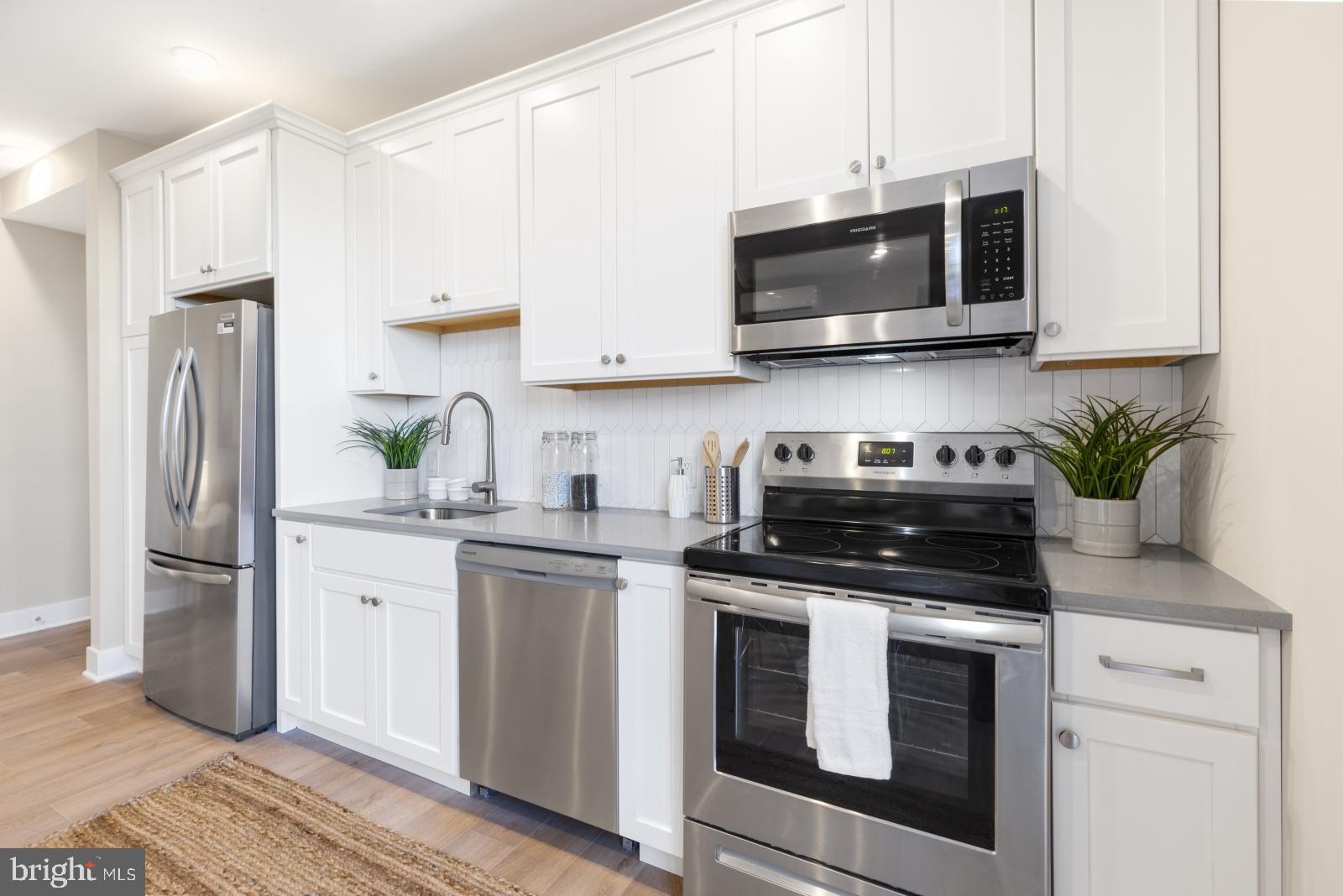 6712 Ridge Avenue, Unit 302 Philadelphia, PA 19128 - Photo 13 of 22 a kitchen with stainless steel appliances granite countertop white cabinets a stove a microwave and a refrigerator