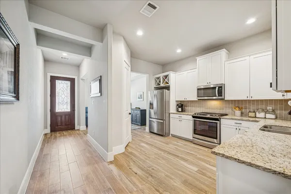 a kitchen with granite countertop white cabinets and stainless steel appliances
