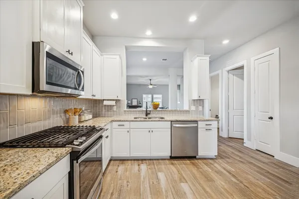 a kitchen with stainless steel appliances granite countertop a stove top oven a sink dishwasher and a refrigerator