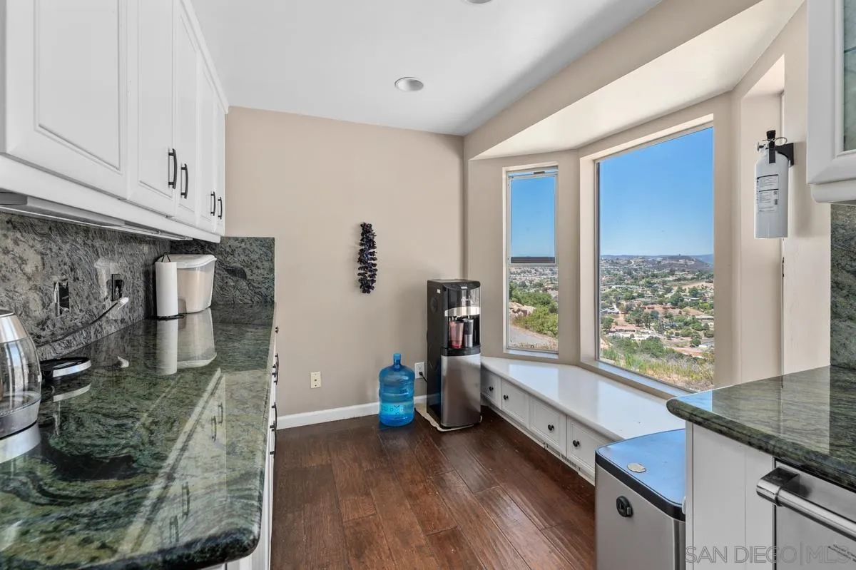 2155 Vista Valley Rim Place El Cajon, CA 92019 - Photo 20 of 61 a kitchen with granite countertop a stove and a wooden floor