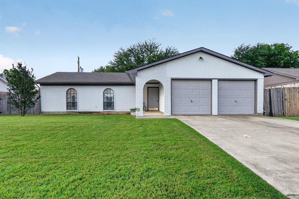 1212 Manning Road Benbrook, TX 76126 - Photo 4 of 20 White brick exterior featuring arched windows, a two-car garage, a concrete driveway, a covered entry, and a front lawn