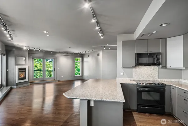 a kitchen with stainless steel appliances granite countertop a sink a stove a microwave a refrigerator cabinets and living room view