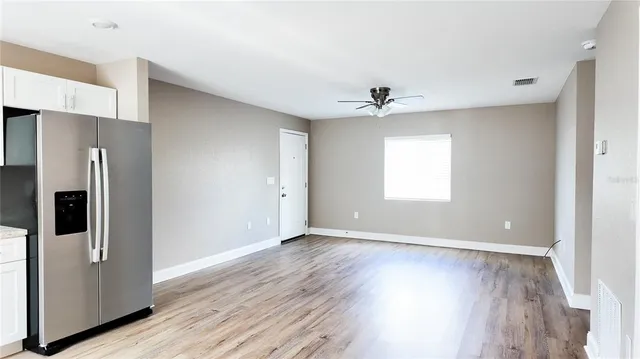a view of an empty room with window and wooden floor