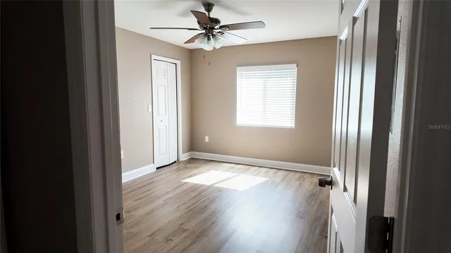 a view of an empty room with window and wooden floor