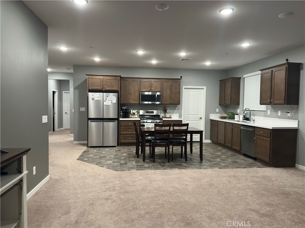 1351 Fiddleleaf Drive Banning, CA 92220 - Photo 2 of 16 a kitchen with stainless steel appliances kitchen island granite countertop a refrigerator a stove a sink a dining table and chairs