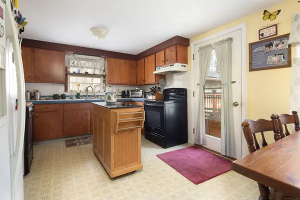 a kitchen with stainless steel appliances granite countertop a stove a refrigerator a sink a dining table and chairs