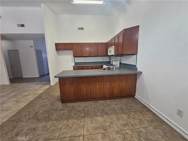 a kitchen with kitchen island granite countertop a stove a sink a refrigerator cabinets and a dining table