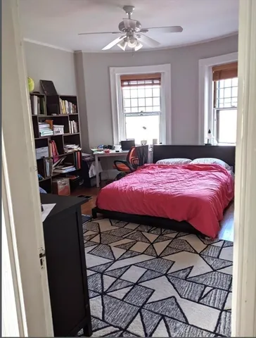 a bedroom with a bed a bookshelf and a window