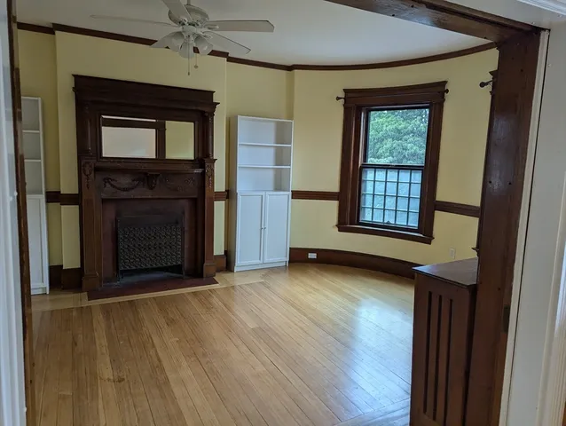 an empty room with wooden floor a ceiling fan and windows