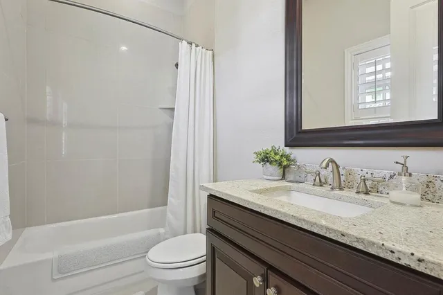 a bathroom with a granite countertop sink a toilet and shower