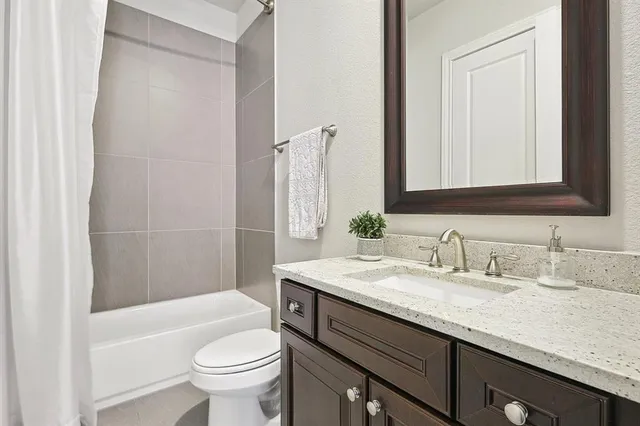 a bathroom with a granite countertop sink a toilet a mirror and bathtub