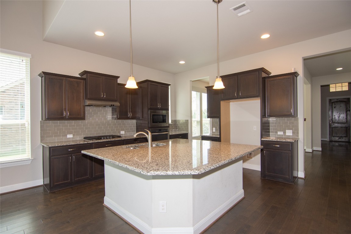 3901 Rhythmic Drive Pflugerville, TX 78660 - Photo 6 of 40 a large kitchen with stainless steel appliances kitchen island granite countertop a sink a stove and a refrigerator
