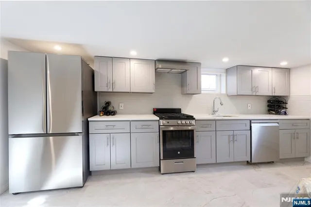 a kitchen with stainless steel appliances granite countertop a refrigerator sink and stove