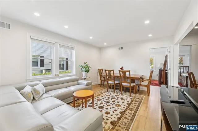 a living room with furniture and a dining table with wooden floor