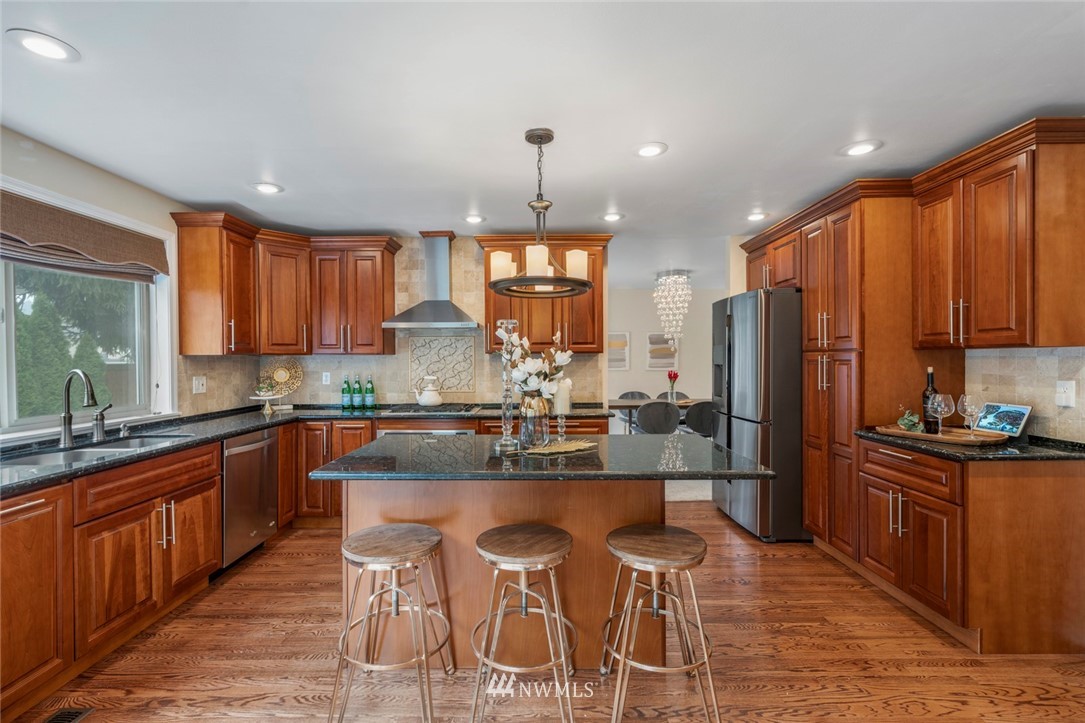 23100 14th Drive Southeast Bothell, WA 98021 - Photo 6 of 30 a kitchen with stainless steel appliances kitchen island granite countertop a refrigerator a sink dishwasher a stove with wooden cabinets and a granite counter top