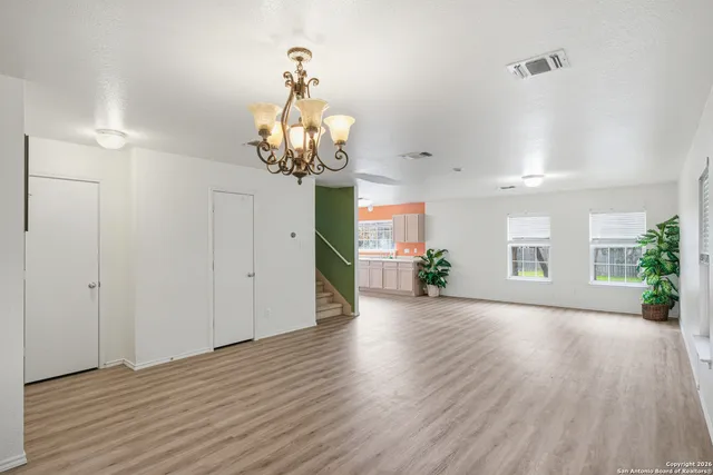 a view of a hallway with wooden floor and a chandelier