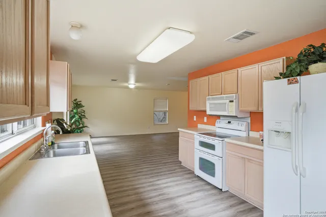 a kitchen with stainless steel appliances a stove a sink and white cabinets with wooden floor