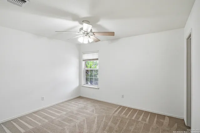 an empty room with a window and a ceiling fan