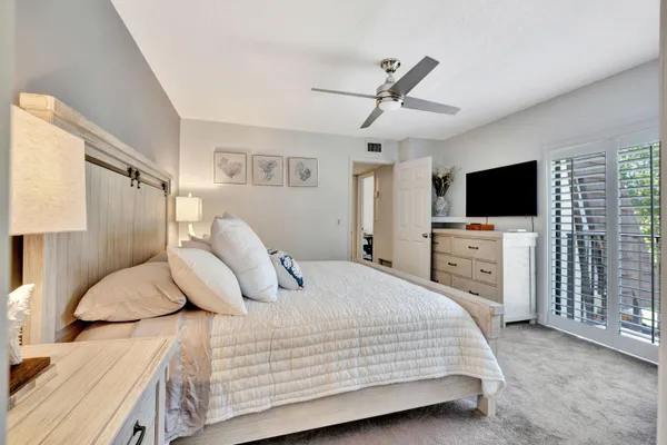 a bedroom with a bed and a flat tv screen on dresser