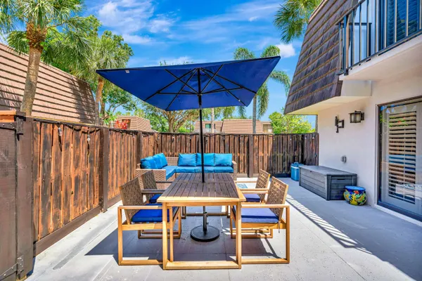 a view of a patio with table and chairs under an umbrella with wooden fence