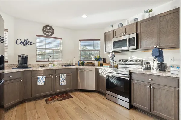 a kitchen with granite countertop a sink cabinets stainless steel appliances and a window