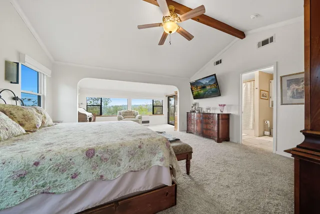 a bedroom with a bed couch and a flat tv screen