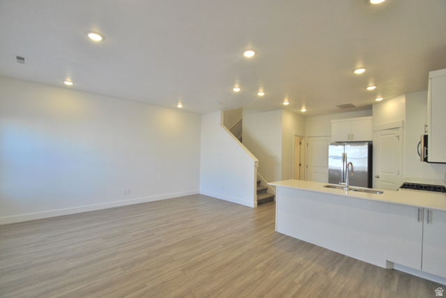 1219 West 1870 South Logan, UT 84321 - Photo 18 of 18 Open Space Living Room, Dining Room and Kitchen, with white cabinets, a peninsula, appliances with stainless steel finishes, light wood-type flooring, and open floor plan