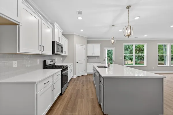 a kitchen with stainless steel appliances granite countertop a sink a stove and a wooden floors