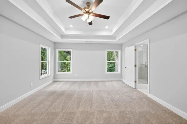 a view of a livingroom with a ceiling fan & windows