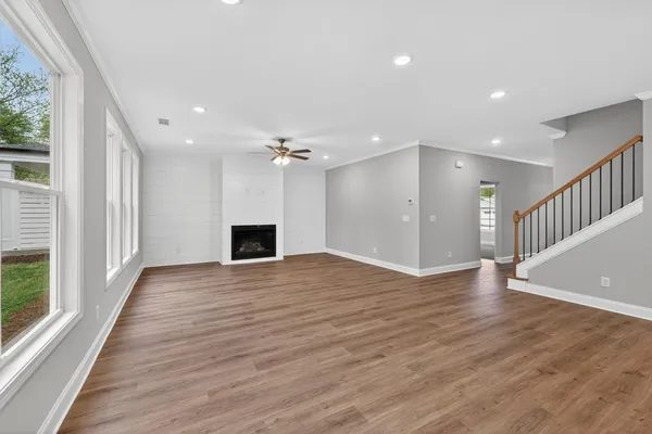 a view of a livingroom with wooden floor and a kitchen space