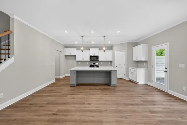 a view of kitchen with kitchen island a sink wooden floor and a refrigerator
