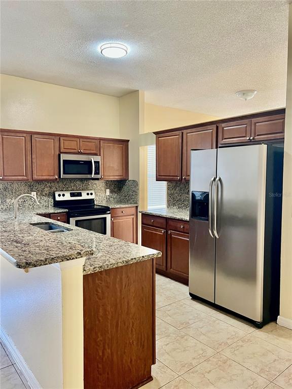 13367 Luxbury Loop Orlando, FL 32837 - Photo 22 of 49 a kitchen with stainless steel appliances granite countertop a refrigerator a stove a sink and a microwave