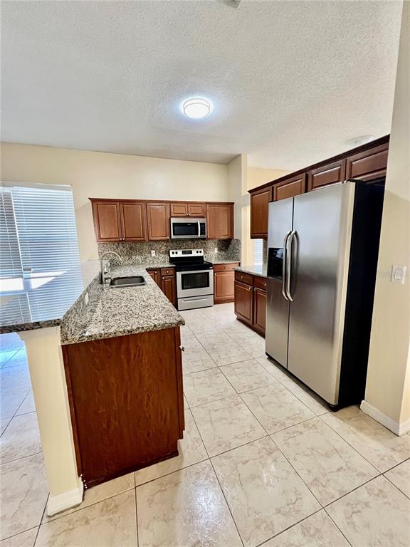 13367 Luxbury Loop Orlando, FL 32837 - Photo 23 of 49 a kitchen with stainless steel appliances granite countertop a refrigerator and a stove