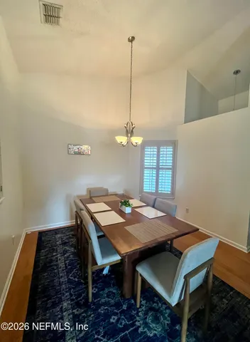 a dining room with wooden floor a chandelier a wooden table and chairs