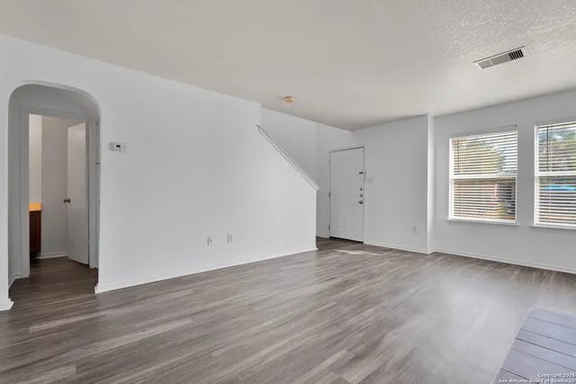 an empty room with wooden floor and windows