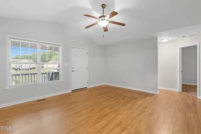 a view of an empty room with wooden floor and windows
