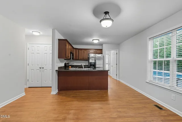 a view of an empty room with a window and wooden floor
