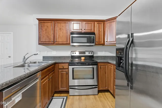 a large kitchen with stainless steel appliances granite countertop a refrigerator oven a sink dishwasher with a dining table and chairs