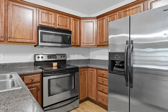 a view of a kitchen with stainless steel appliances wooden floor and a window