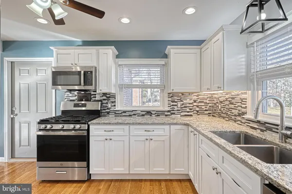 a kitchen with granite countertop a sink stainless steel appliances and cabinets