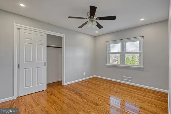 a view of empty room with wooden floor and fan