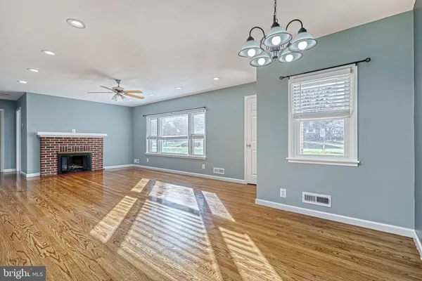 a view of an empty room with chandelier and fireplace