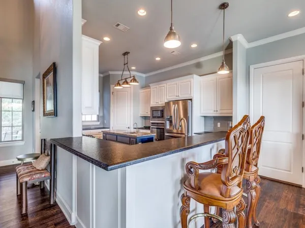 a kitchen with stainless steel appliances kitchen island granite countertop a sink a stove a dining table and chairs