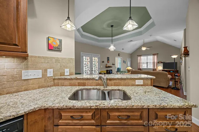a kitchen with kitchen island granite countertop a sink a counter space appliances and cabinets