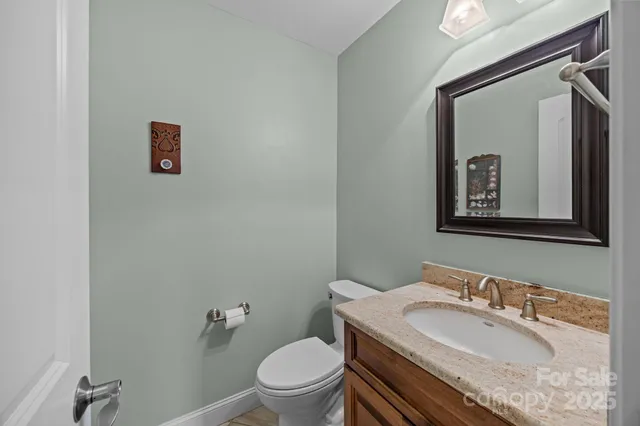 a bathroom with a granite countertop toilet a sink and mirror