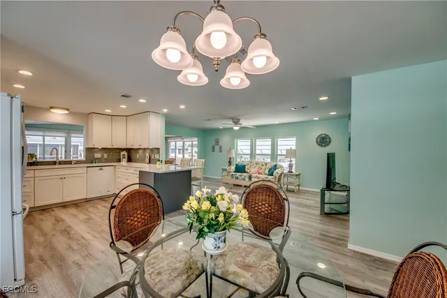 a kitchen with stainless steel appliances granite countertop a table chairs refrigerator and sink