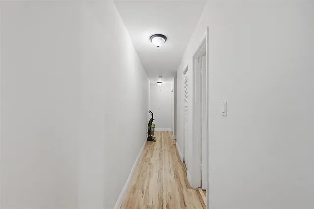 a view of a hallway with wooden floor and a bathroom