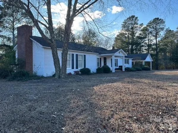 a view of a house with a yard and large tree