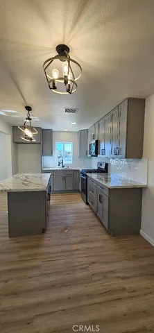 a large kitchen with stainless steel appliances a large counter top a stove and a refrigerator