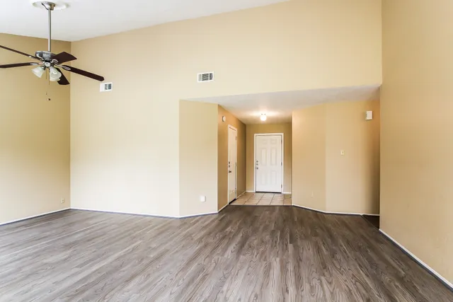 a view of a room with wooden floor and a ceiling fan